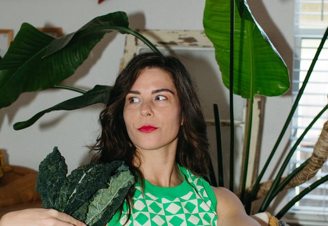 Jessi holding a bunch of kale, seated beside a disco ball