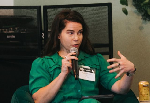 Jessi on a panel with a microphone, mid-gesture