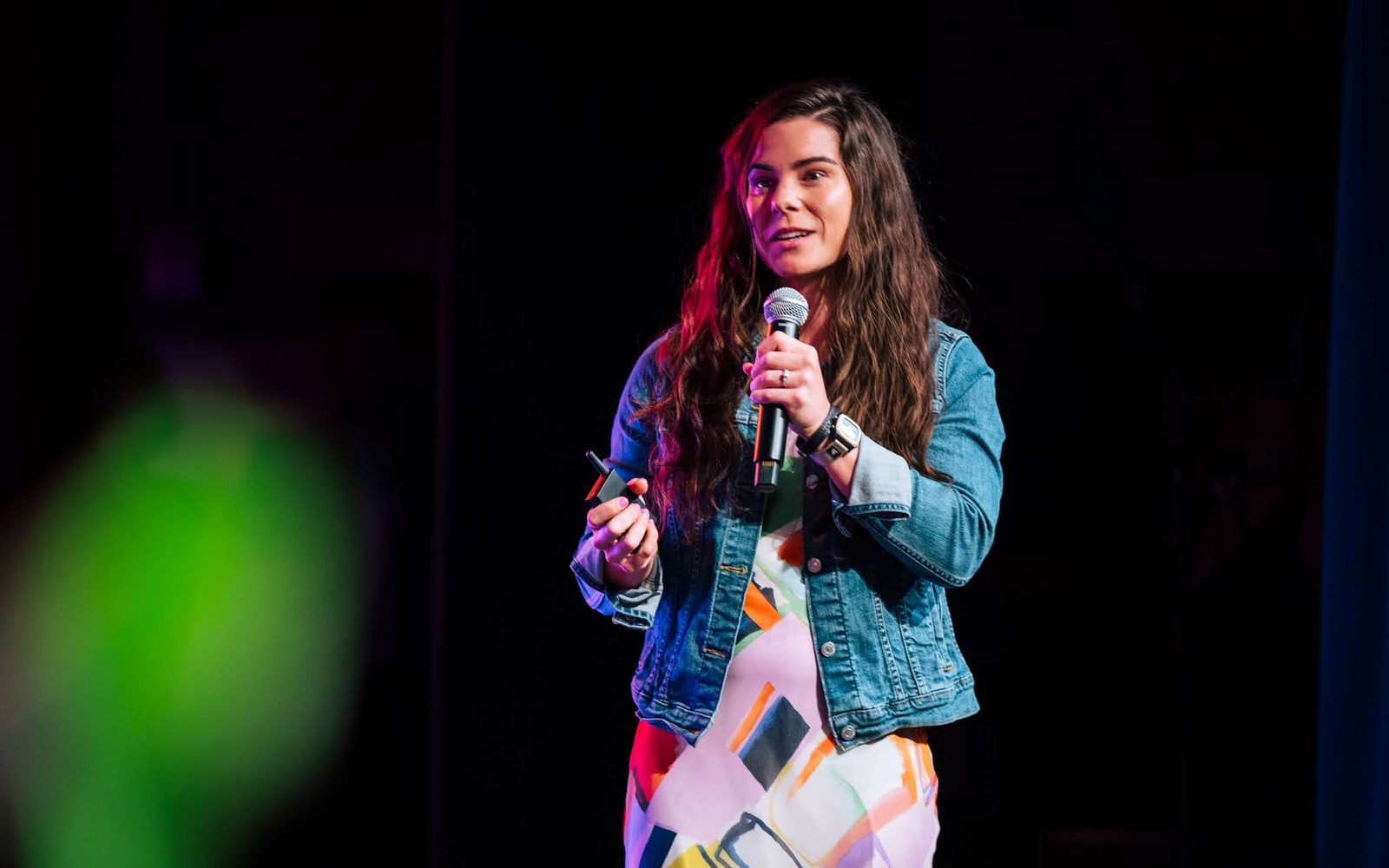 Jessi on stage with a microphone in a denim jacket